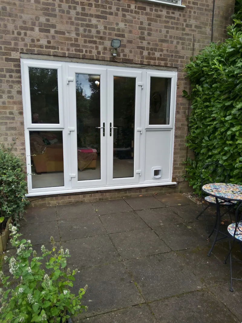 White uPVC French doors with a matching side panel, opening from a rendered elevation onto a paved patio with a garden beyond.